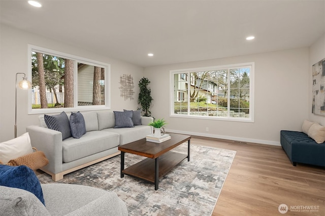 living area with baseboards, wood finished floors, and recessed lighting