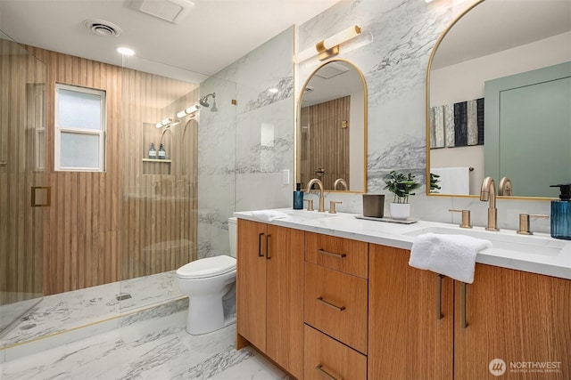 full bath featuring double vanity, a stall shower, visible vents, marble finish floor, and a sink