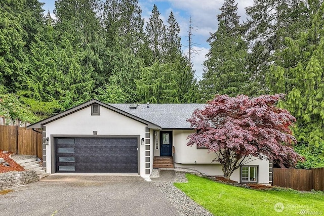 single story home with a garage, aphalt driveway, fence, a front lawn, and stucco siding