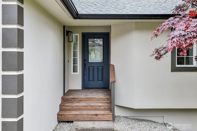 entrance to property with roof with shingles and stucco siding