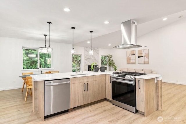 kitchen with stainless steel appliances, light countertops, light brown cabinets, a sink, and exhaust hood