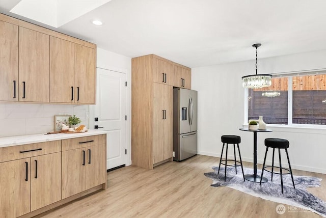 kitchen featuring light wood-type flooring, light brown cabinets, backsplash, and stainless steel fridge with ice dispenser