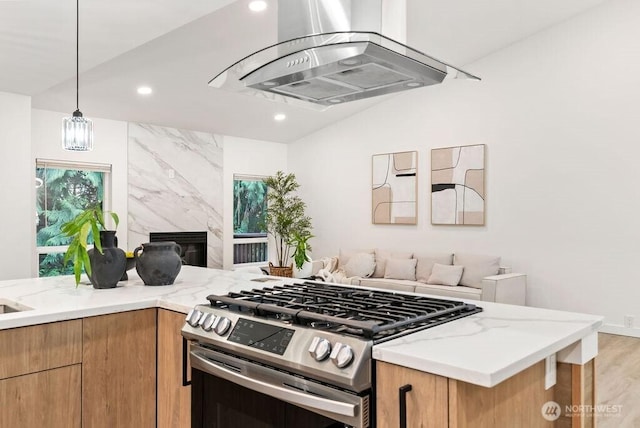 kitchen with light stone counters, a wealth of natural light, open floor plan, stainless steel gas range oven, and wall chimney exhaust hood