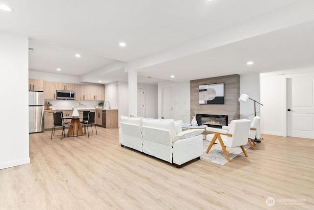 living room featuring light wood finished floors, a fireplace, recessed lighting, and baseboards