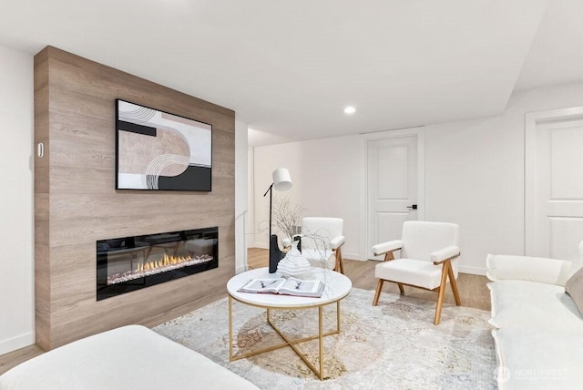 living area featuring a large fireplace, recessed lighting, wood finished floors, and baseboards