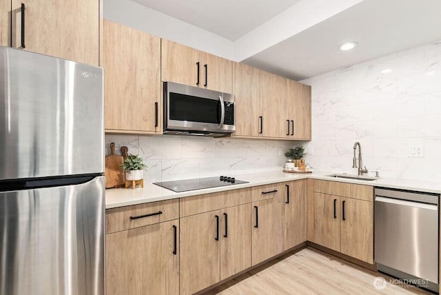 kitchen with light brown cabinetry, appliances with stainless steel finishes, a sink, and decorative backsplash