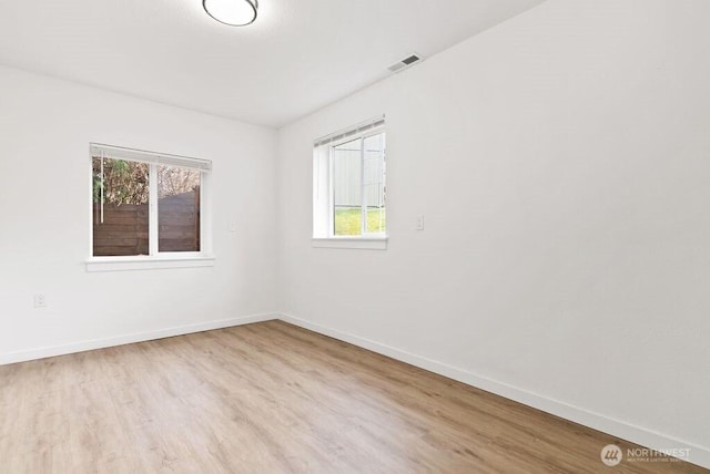 unfurnished room with visible vents, baseboards, and wood finished floors