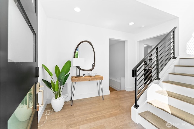 foyer entrance featuring baseboards, light wood finished floors, stairs, and recessed lighting