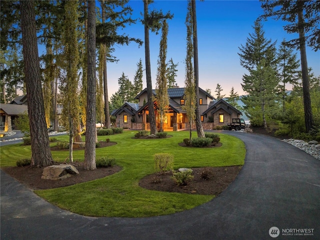 view of front of house with driveway, a lawn, and stone siding