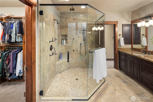 bathroom with a spacious closet, a shower stall, and vanity