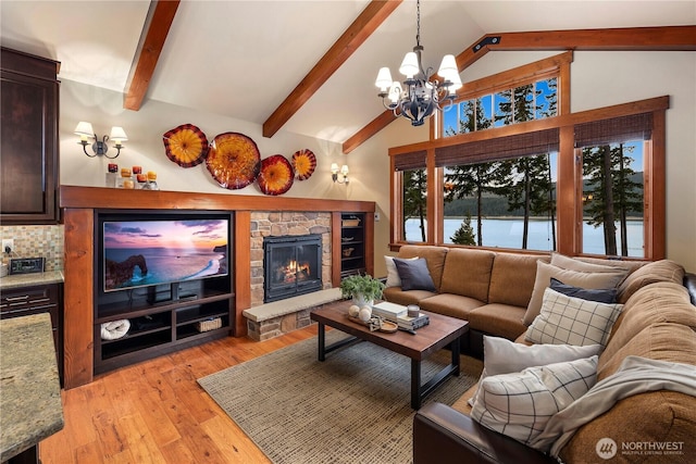 living room featuring light wood-style floors, a chandelier, vaulted ceiling with beams, and a stone fireplace