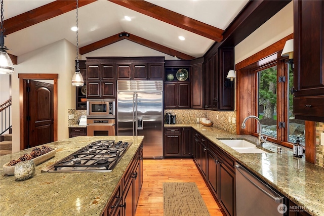 kitchen with lofted ceiling with beams, light stone counters, a sink, and built in appliances