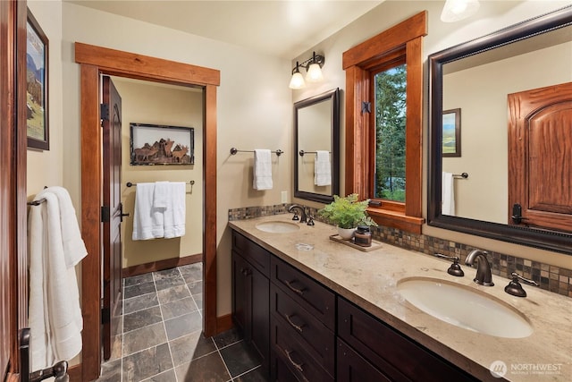 full bath featuring double vanity, baseboards, and a sink