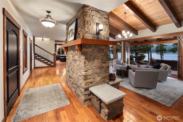 living room featuring lofted ceiling with beams, wood ceiling, light wood-style flooring, stairway, and a chandelier