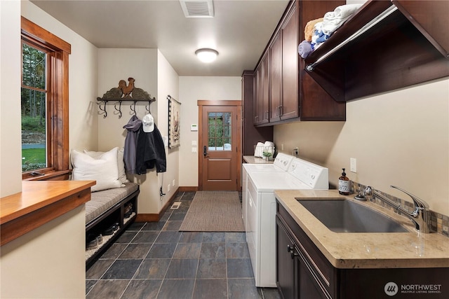 washroom featuring cabinet space, baseboards, visible vents, independent washer and dryer, and a sink