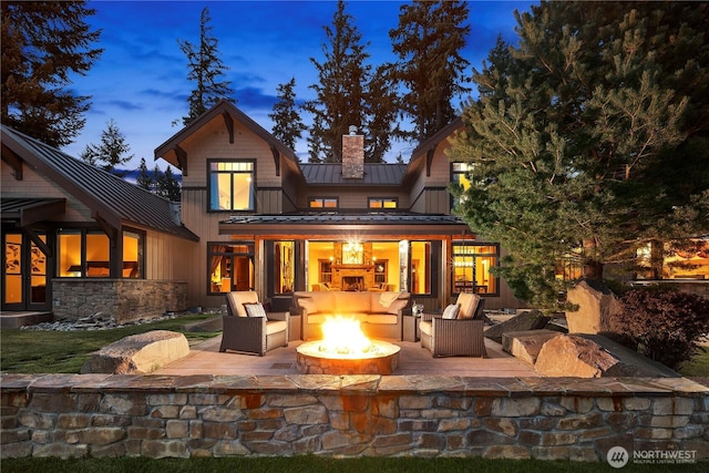 back of property featuring an outdoor fire pit, a chimney, metal roof, a standing seam roof, and a patio area