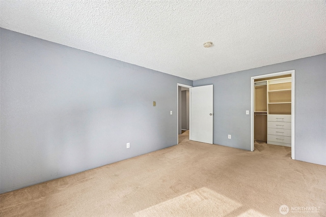 unfurnished bedroom featuring a walk in closet, carpet, a closet, and a textured ceiling