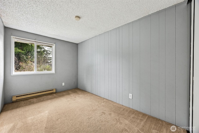 spare room featuring a textured ceiling, a baseboard heating unit, and carpet floors