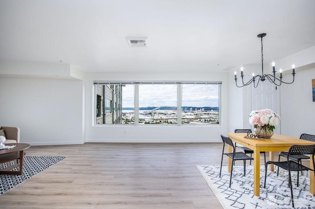 dining room with visible vents, light wood-style flooring, baseboards, and an inviting chandelier