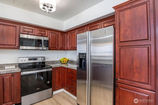kitchen featuring stainless steel appliances, light wood-style floors, and dark brown cabinets