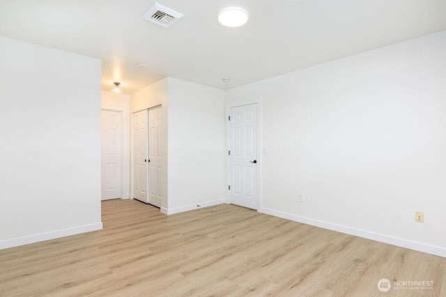 unfurnished room with light wood-style flooring, visible vents, and baseboards