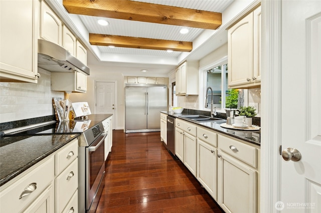 kitchen with appliances with stainless steel finishes, a sink, beam ceiling, and under cabinet range hood