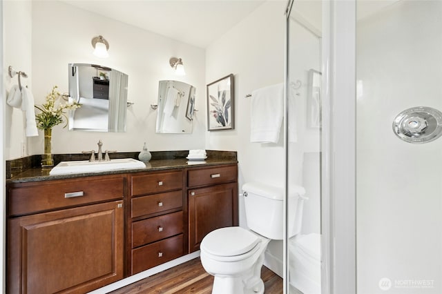 bathroom with toilet, an enclosed shower, wood finished floors, and vanity