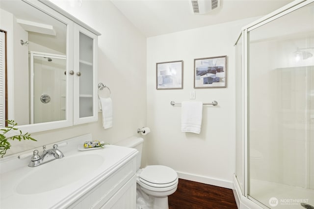 full bathroom featuring a stall shower, visible vents, toilet, wood finished floors, and vanity