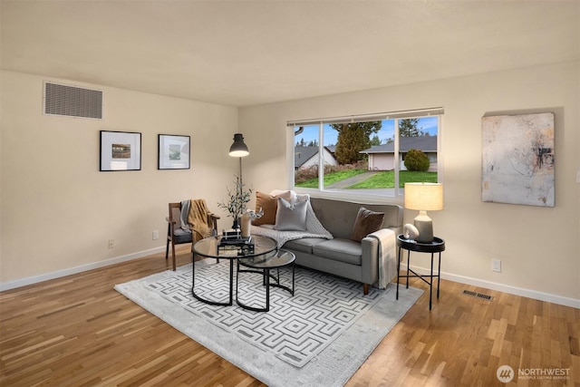 living area featuring baseboards, visible vents, and wood finished floors