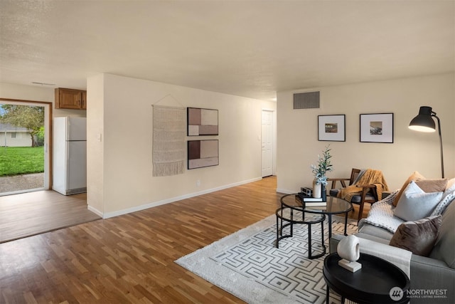 living room with visible vents, baseboards, and wood finished floors