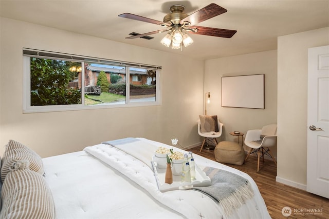 bedroom with a ceiling fan, baseboards, and wood finished floors