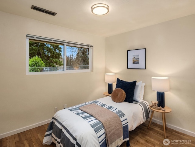 bedroom featuring wood finished floors, visible vents, and baseboards