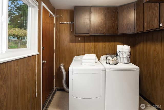 laundry room featuring cabinet space, wooden walls, and independent washer and dryer