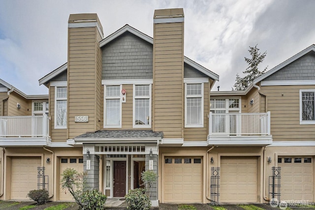 townhome / multi-family property with a garage, a chimney, and a balcony