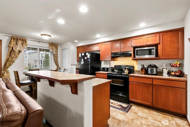 kitchen with recessed lighting, under cabinet range hood, a breakfast bar, light countertops, and black appliances