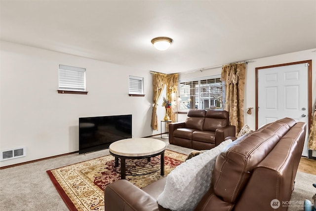 carpeted living area featuring a fireplace, visible vents, and baseboards