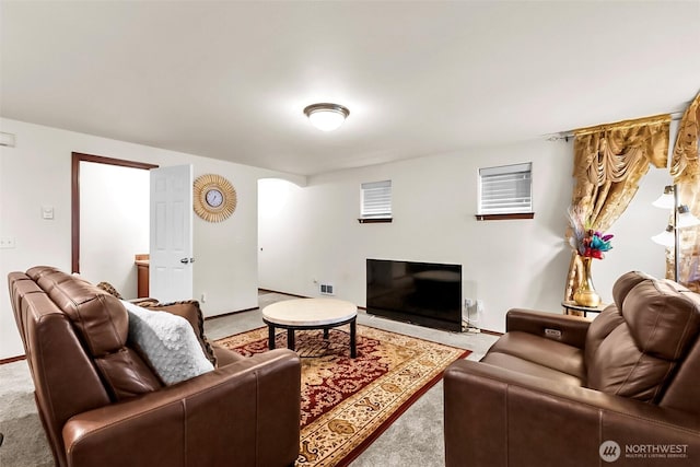 living area featuring arched walkways, carpet flooring, and baseboards