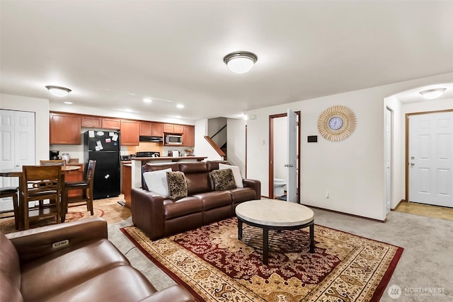 living area with arched walkways, recessed lighting, light carpet, baseboards, and stairs