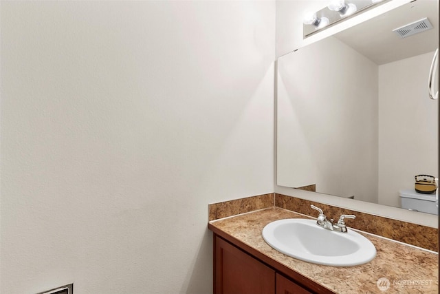 bathroom with toilet, visible vents, and vanity