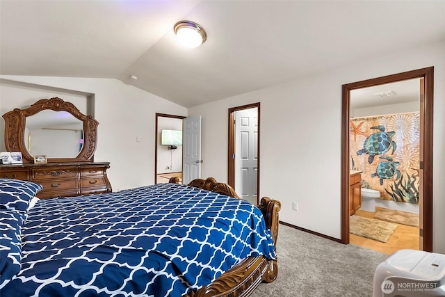 carpeted bedroom featuring lofted ceiling, connected bathroom, and baseboards