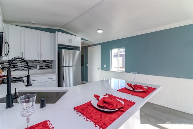 kitchen featuring wainscoting, light countertops, a sink, and freestanding refrigerator