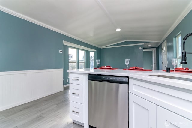 kitchen with white cabinets, wainscoting, crown molding, stainless steel dishwasher, and a sink