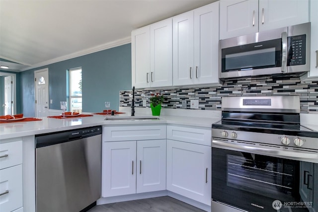 kitchen featuring appliances with stainless steel finishes, light countertops, a sink, and white cabinetry