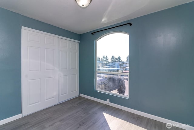 unfurnished bedroom featuring baseboards, a closet, and wood finished floors