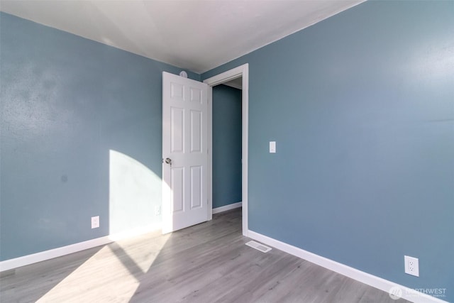 unfurnished room with wood finished floors, visible vents, and baseboards