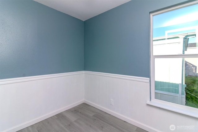 spare room featuring wood finished floors and wainscoting