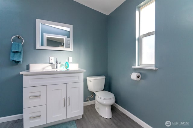 bathroom with baseboards, vanity, toilet, and wood finished floors