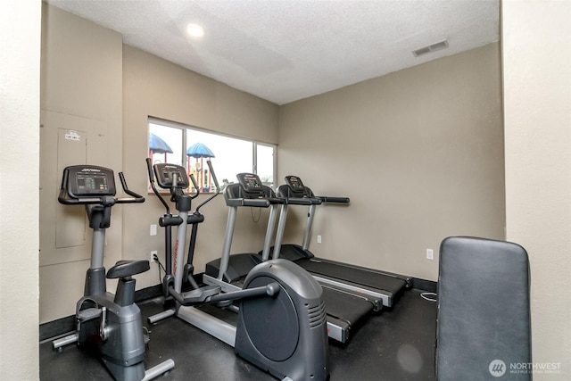 workout room with visible vents, a textured ceiling, and baseboards