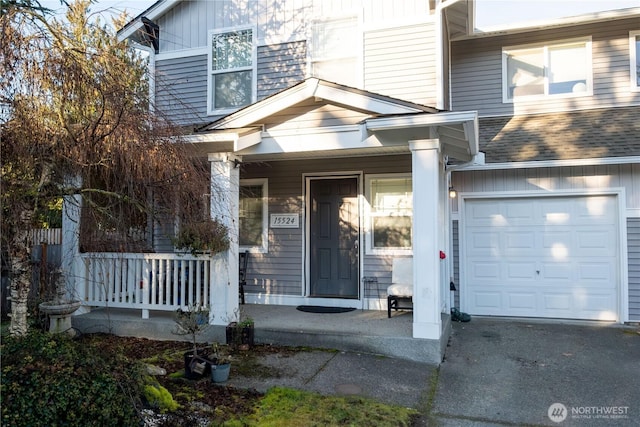 property entrance with covered porch, driveway, a shingled roof, and board and batten siding