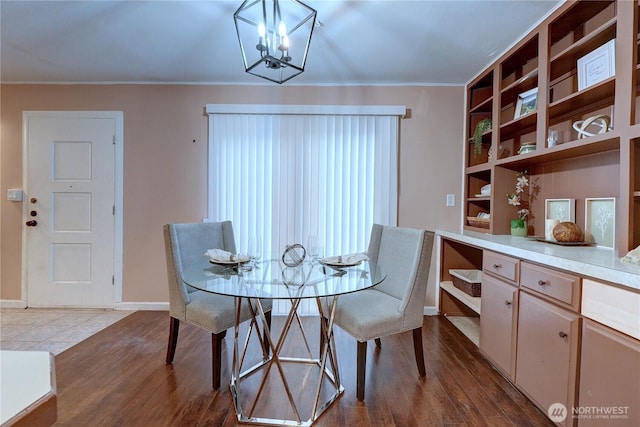 dining space featuring baseboards, a chandelier, crown molding, and wood finished floors